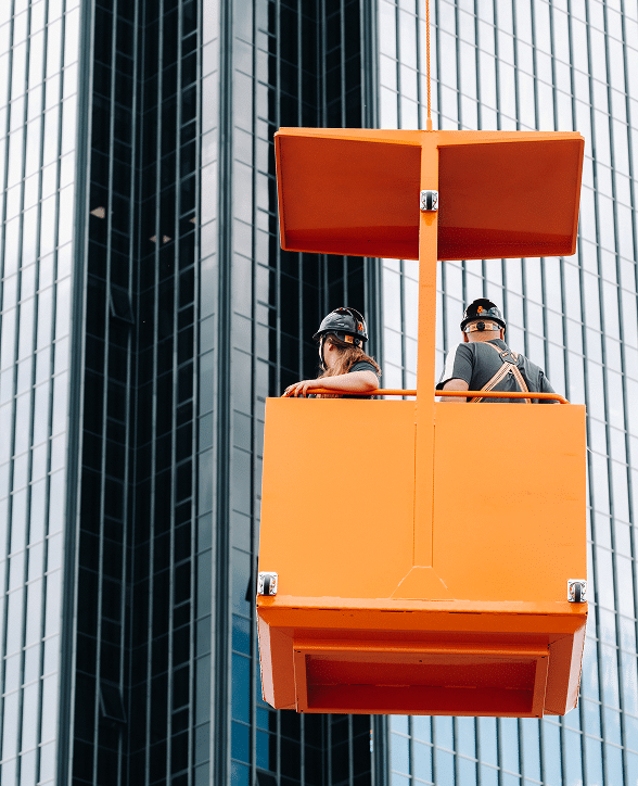Construction workers on a suspended lift on a high-rise building – builder's risk insurance Nebraska | CRS Group