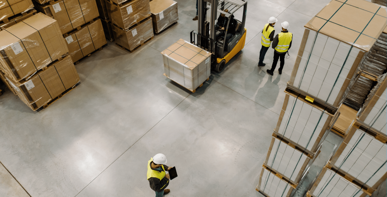 Warehouse workers in hard hats operating forklift with stacked inventory – commercial insurance Nebraska | CRS Group